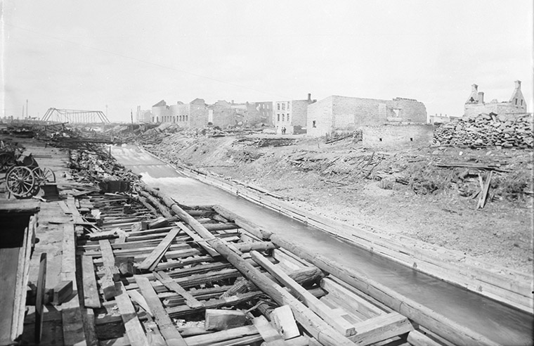 Ruins for Mr. Bronson after the Great Ottawa-Hull Fire of 1900. Booth Street Bridge visible in the distance. Photo credit: Topley Studio / Library and Archives Canada.