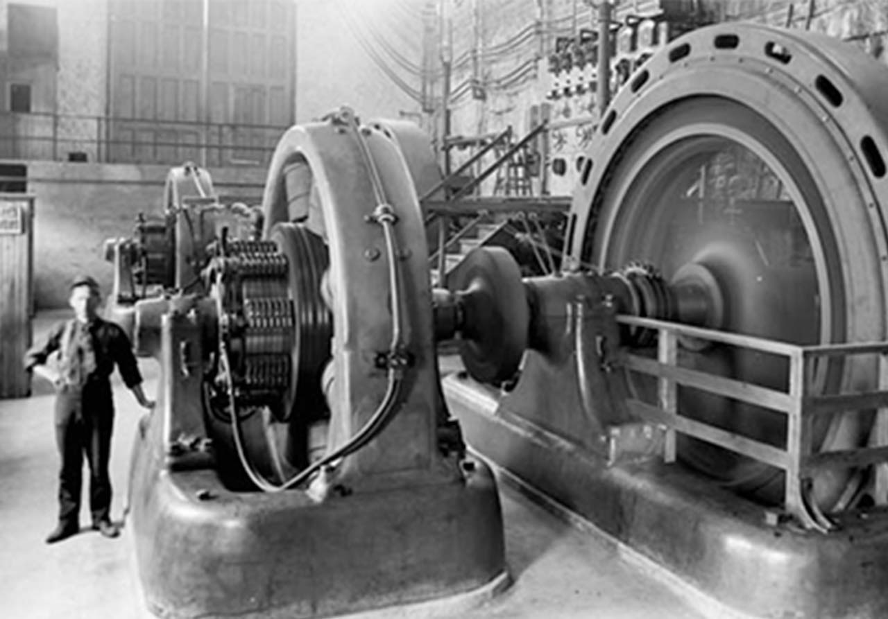 Black and white photo of inside a generating station in the early 1900s.